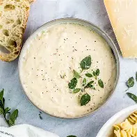Bowl of creamy white sauce garnished with herbs