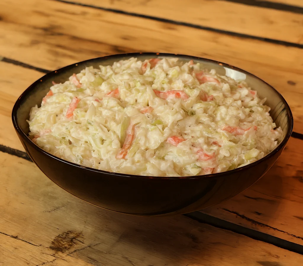 Bowl of creamy coleslaw on wooden table