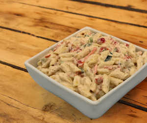 Creamy penne pasta salad in white bowl
