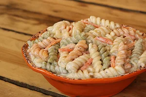 Tri-color rotini pasta in orange bowl